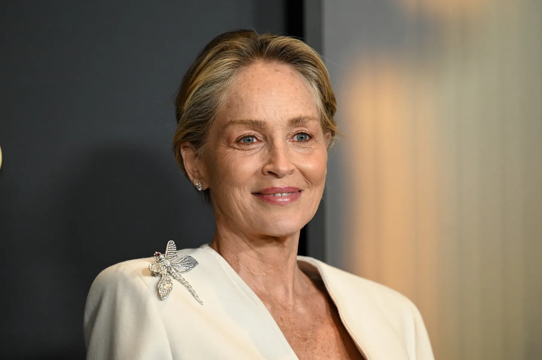 A close-up of Sharon Stone smiling at the Governors Awards in 2024. She's wearing a cream blazer. 