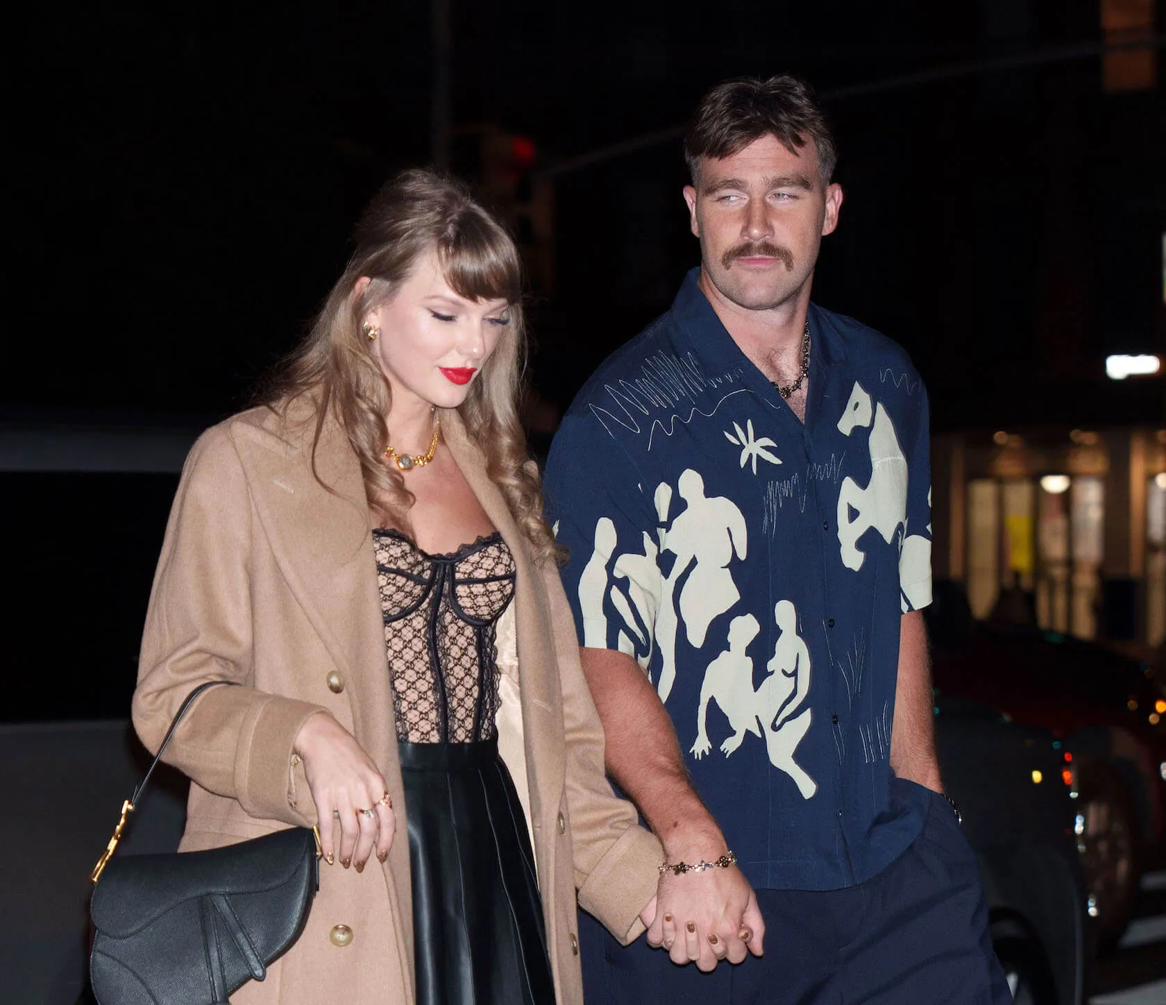 Taylor Swift and Travis Kelce walking hand in hand at night in New York City in October 2024