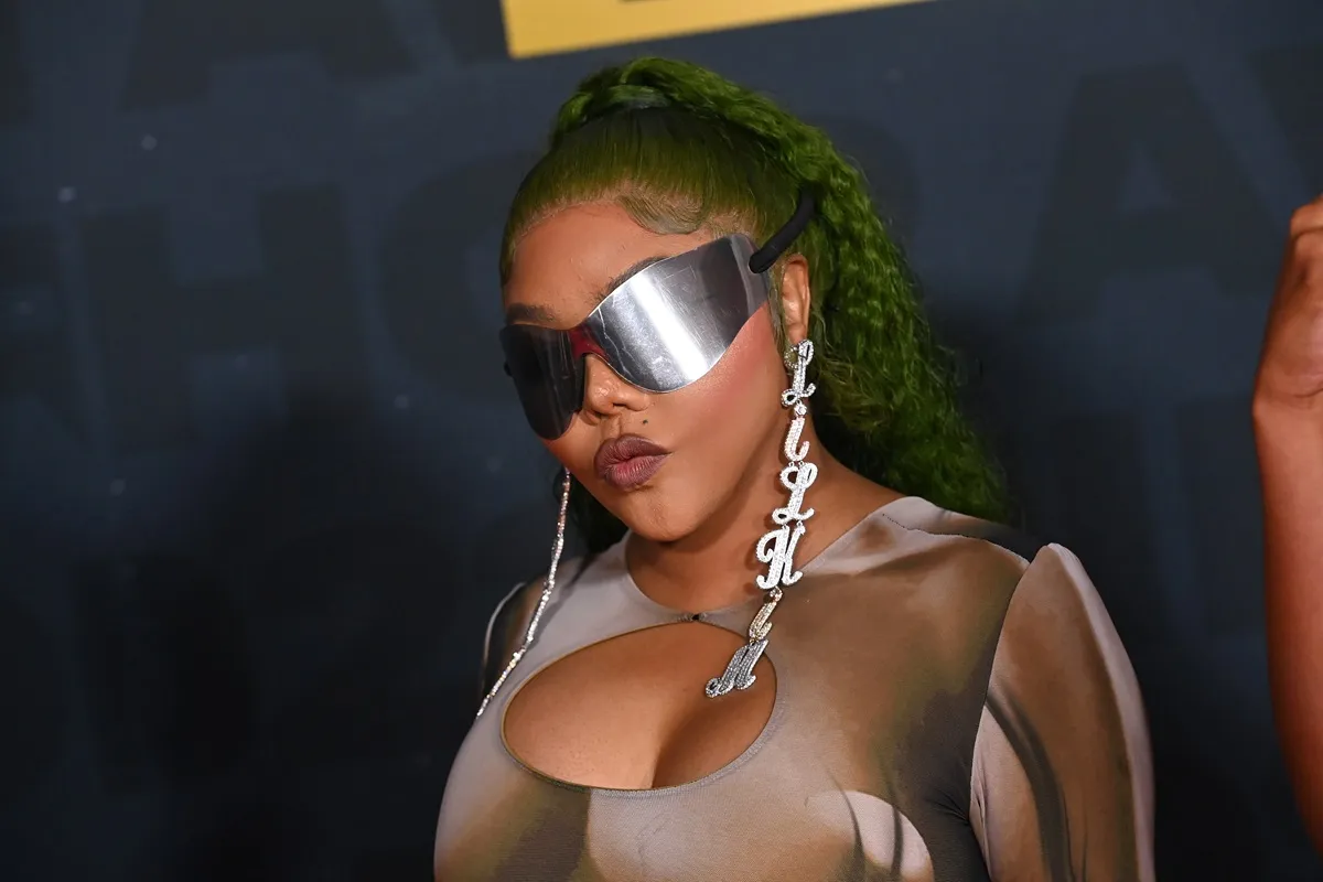 Lil' Kim posing at the BET Hip Hop Awards wearing sunglasses and a brown dress.