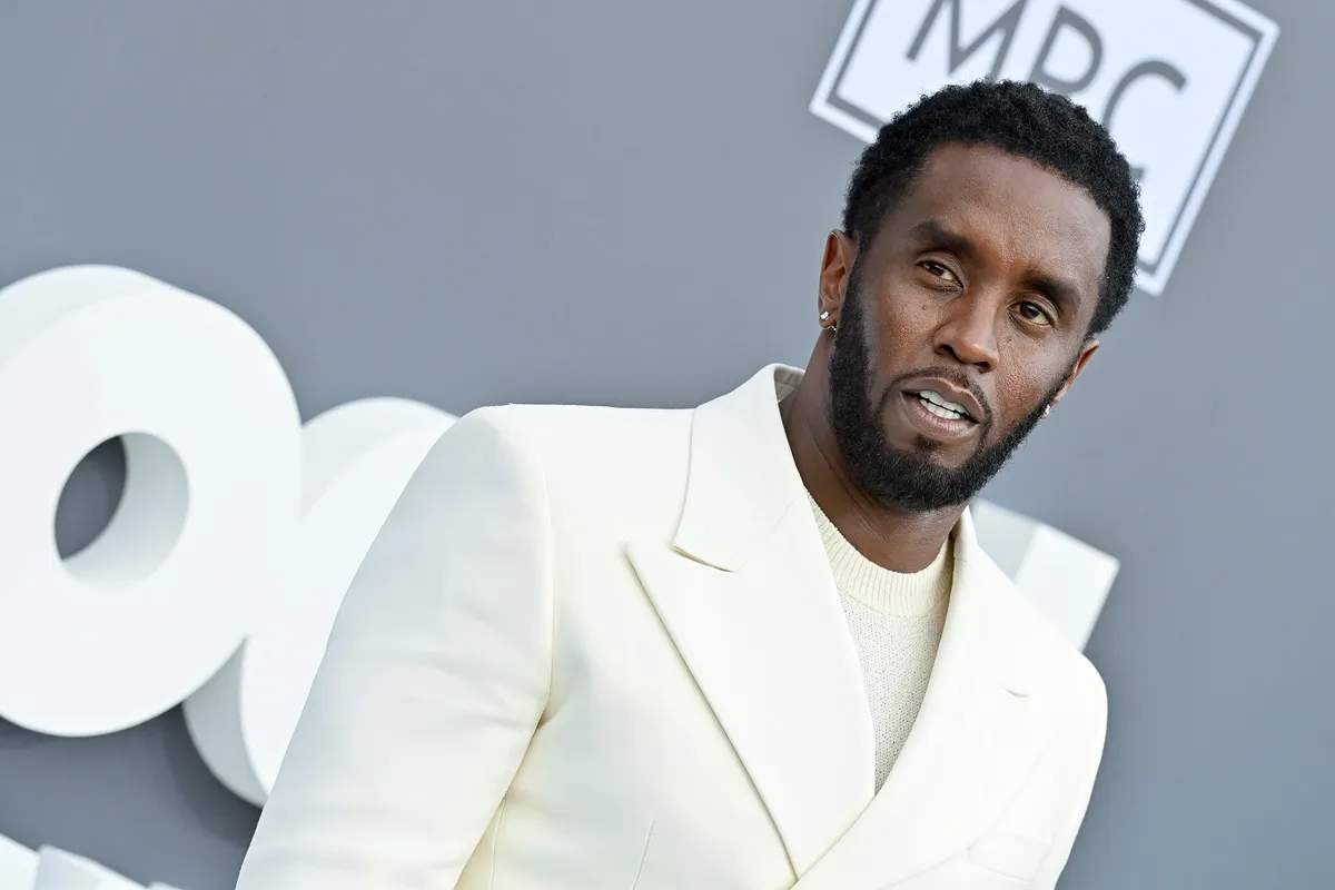 Sean Diddy Combs posing in a white suit at the Billboard music awards.