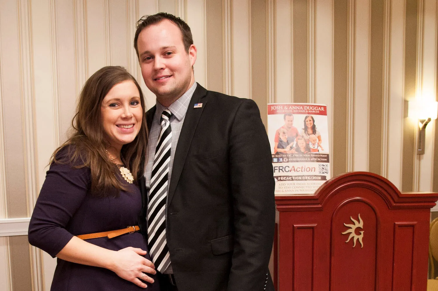 Anna Duggar and Josh Duggar pose during the 42nd annual Conservative Political Action Conference (CPAC). Anna is smiling and cradling her pregnant belly. Josh has his arm around her and is also smiling.