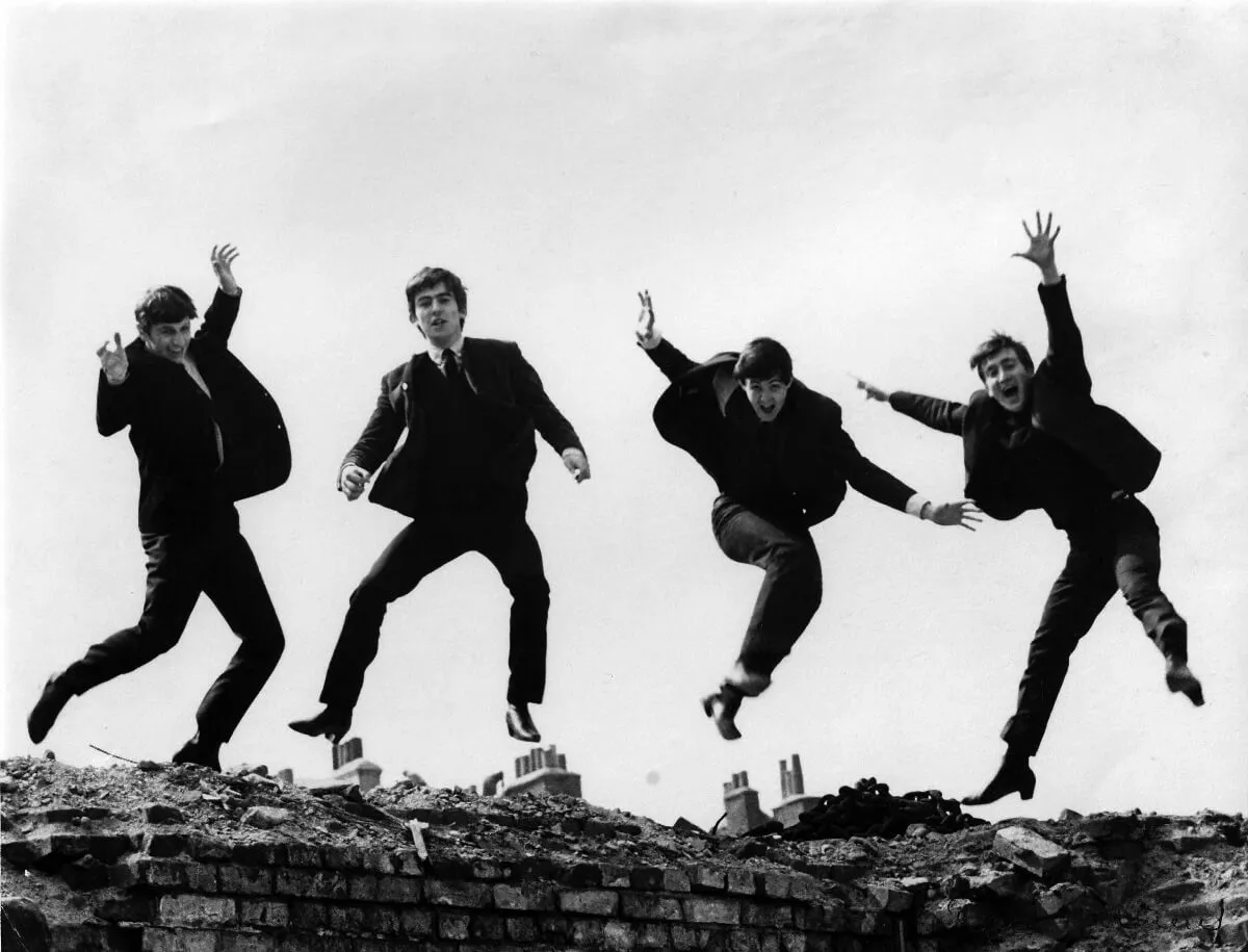 A black and white picture of The Beatles jumping off a wall.