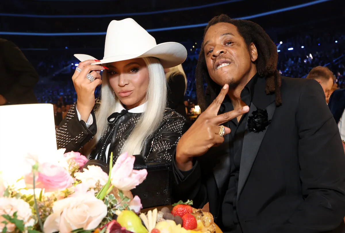 Beyoncé posing in a white cowboy hat while sitting next to Jay-Z, who's flashing a peace sign at the camera at the Grammy Awards