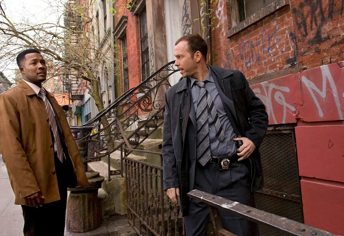 Donnie Wahlberg turns to talk to another man while standing in front of a rowhouse in 'Blue Blood'