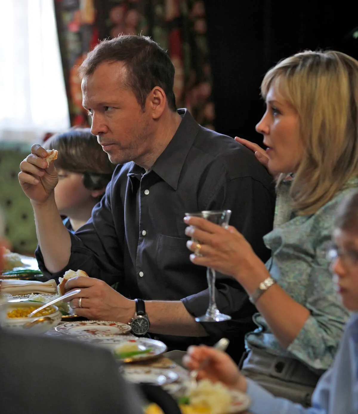 Donnie Wahlberg and a blonde woman sitting at a dinner table in 'Blue Bloods'