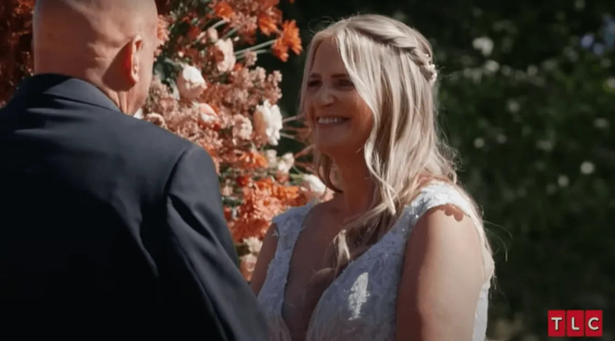 Smiling Christine Brown faces David Woolley at the altar on her wedding day