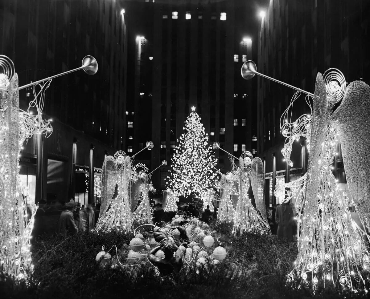 A black and white picture of illuminated angels and a Christmas tree at Rockefeller center.