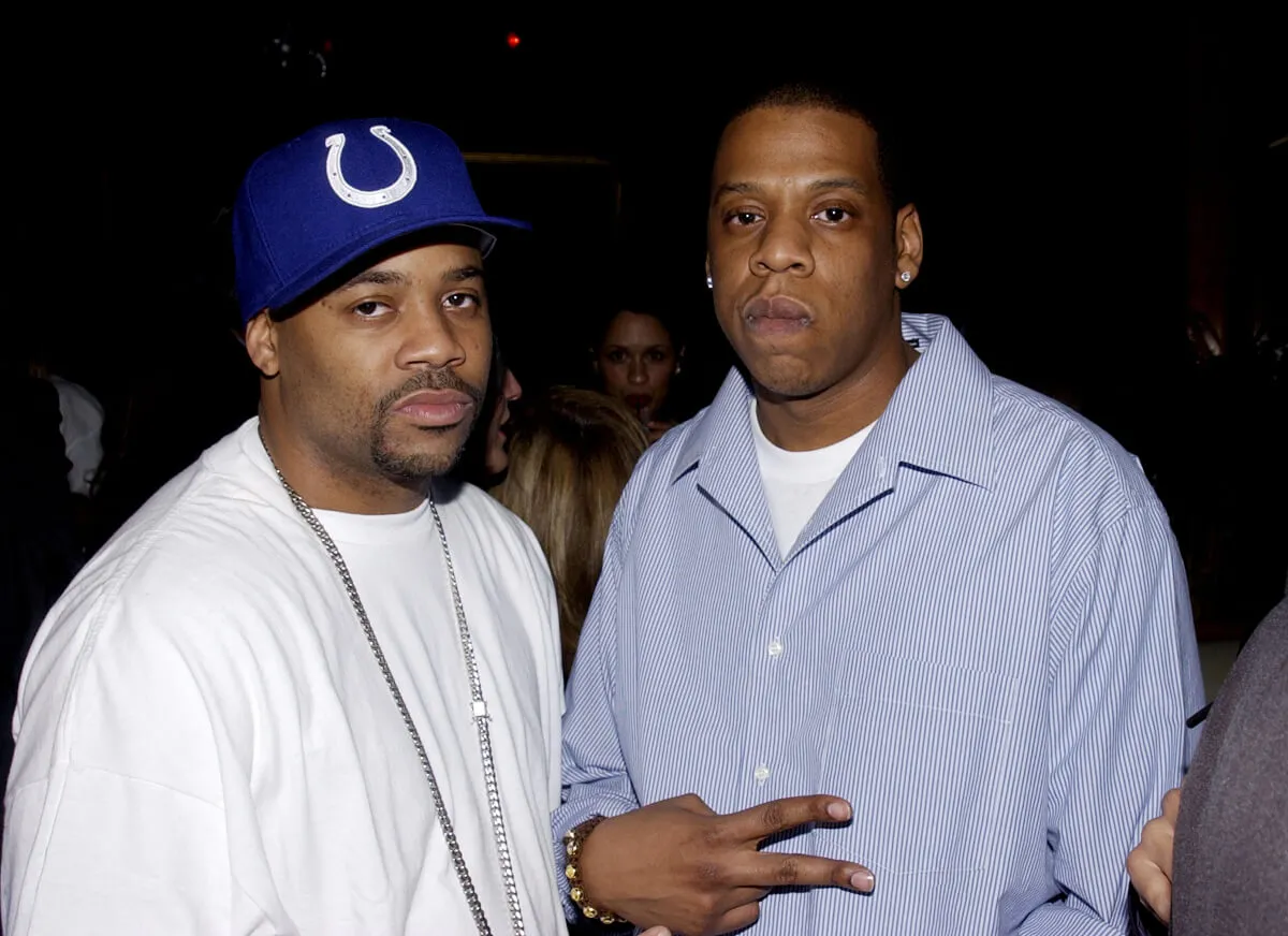 Damon Dash wears a white shirt and Colts hat and stands with Jay-Z, who wears a blue button-down.