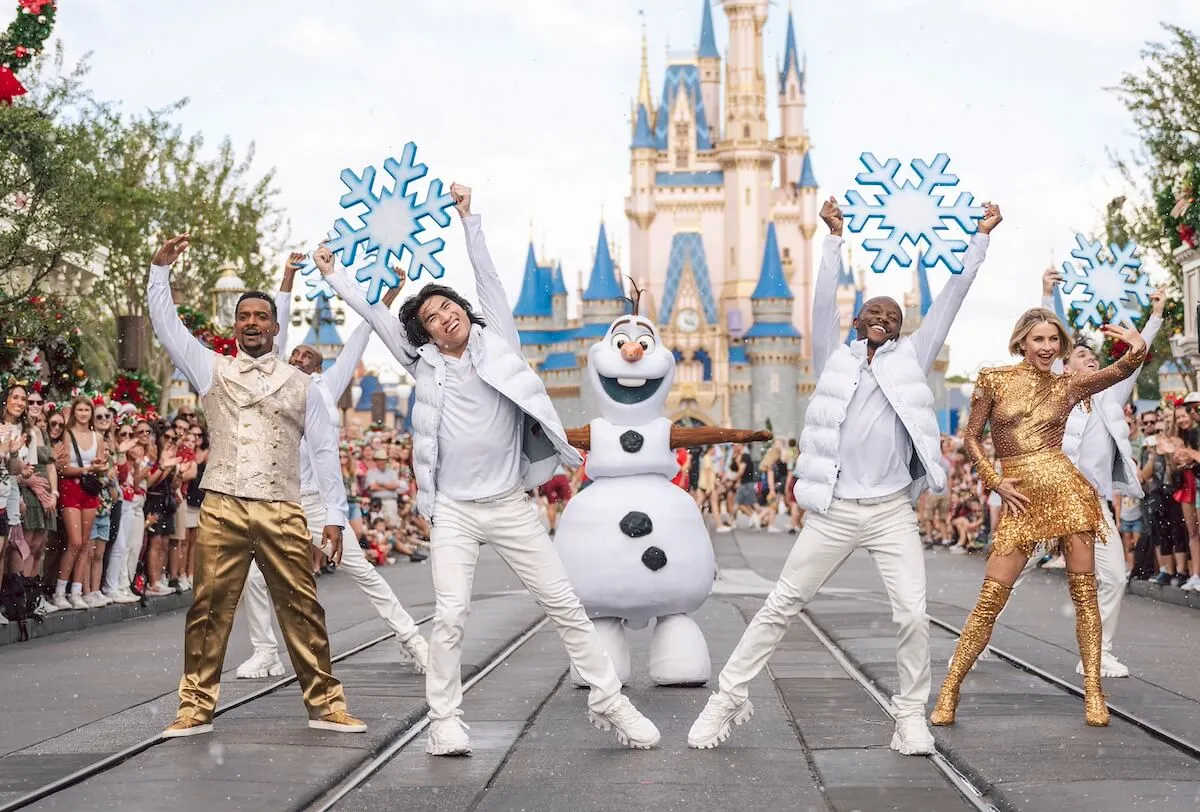 People dressed in white dance with Olaf from 'Frozen' in front of a Disney castle