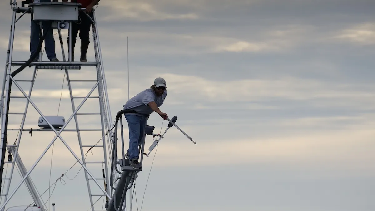 A fisherman aims a harpoon