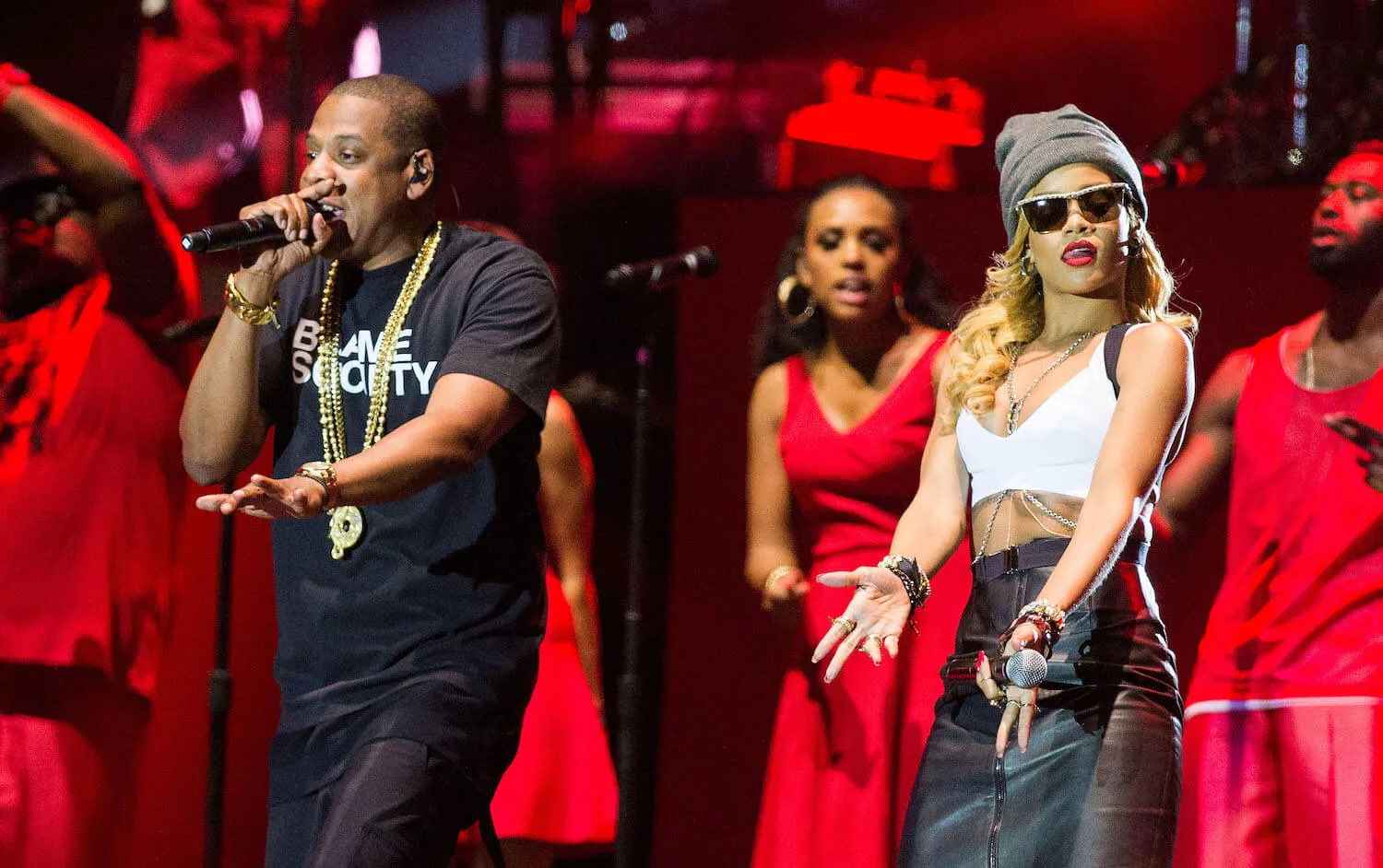 Jay-Z and Rihanna performing on stage with backup dancers behind them wearing red