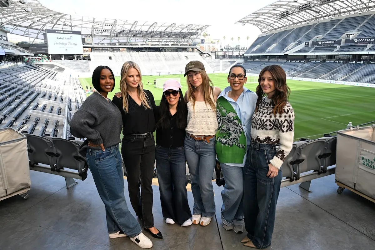 Wearing a gray sweater and baggy denim, Kelly Rowland poses with Kelly Rowland, Baby2Baby Co-CEO Kelly Sawyer Patricof, Ali Wong, Olivia Wilde, Whitney Alford, and Baby2Baby Co-CEO Norah Weinstein at the Baby2Baby Holiday Event