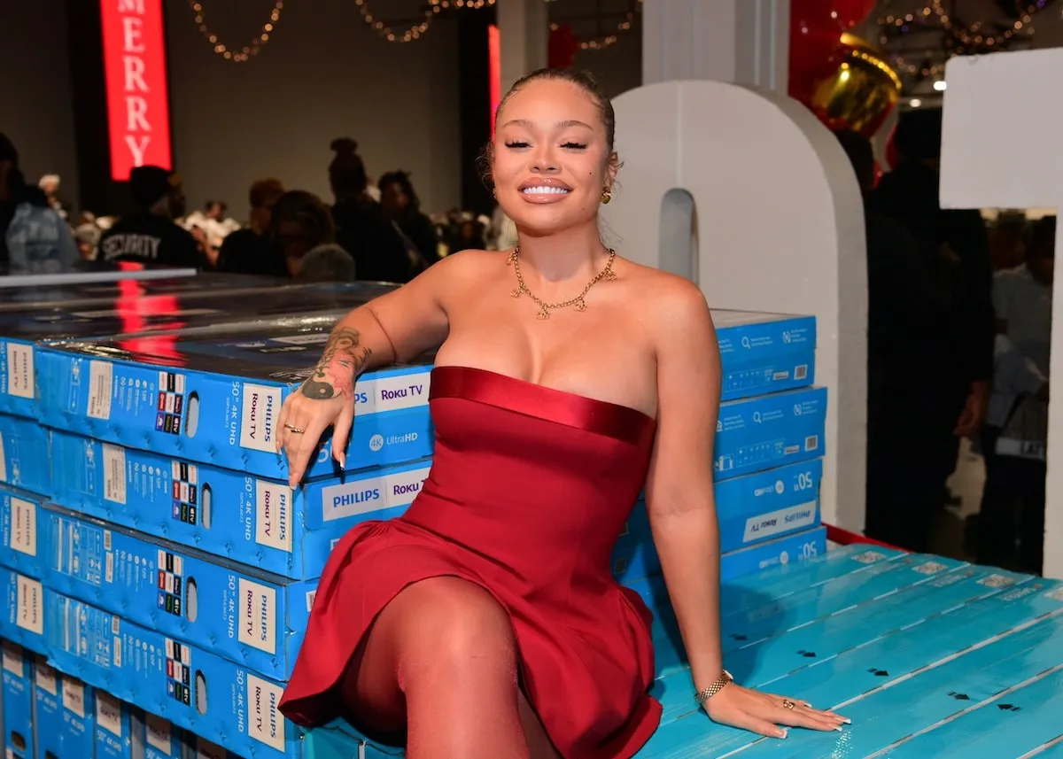 Wearing a red dress, Latto sits on a pile of gifts at the fourth annual 'Christmas In Clayco'