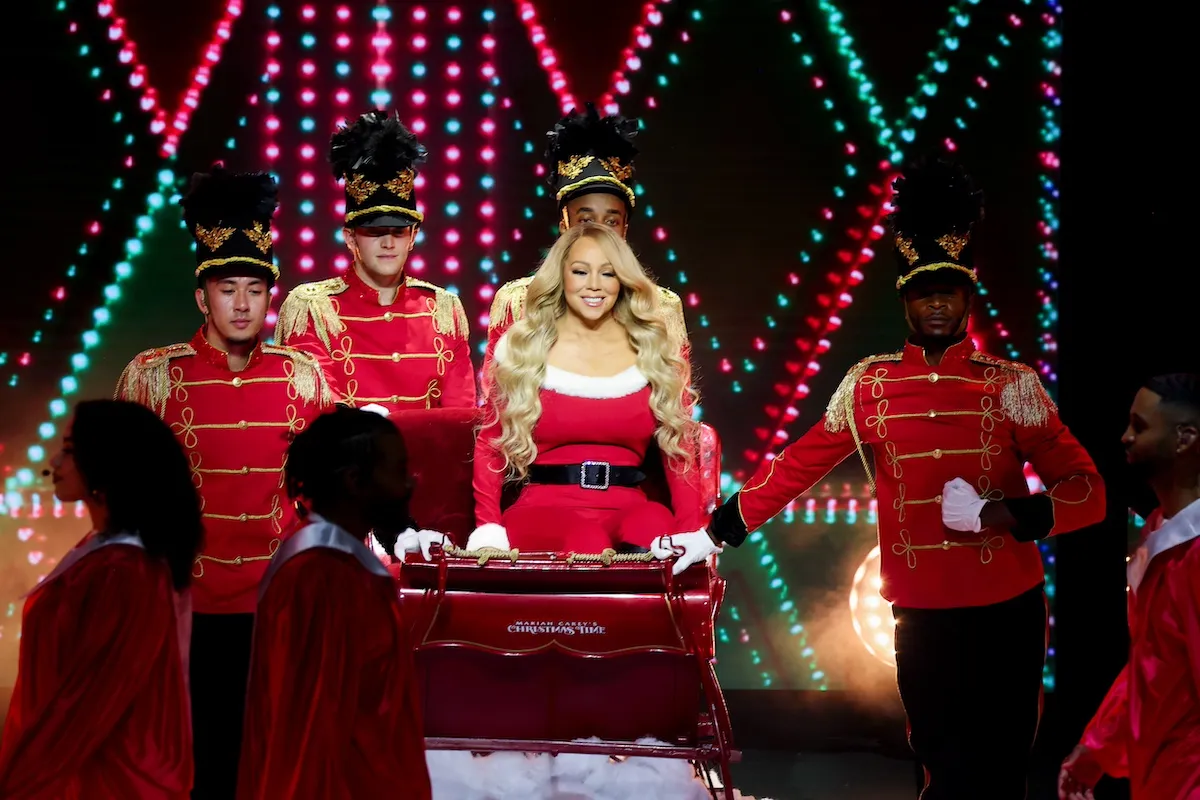 Mariah Carey in a Santa outfit and surrounded by men dressed as wooden soldiers