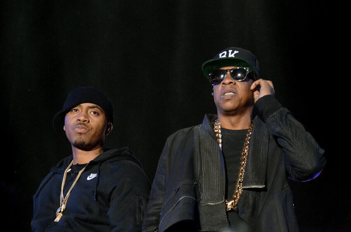 Nas and Jay-Z wear black outfits. Jay-Z wears sunglasses.