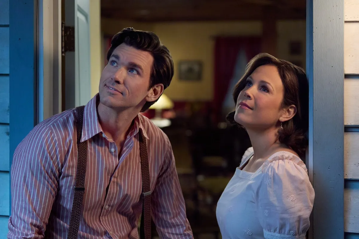 Nathan, in a striped shirt with suspenders, and Elizabeth in a white top, both looking up toward the sky