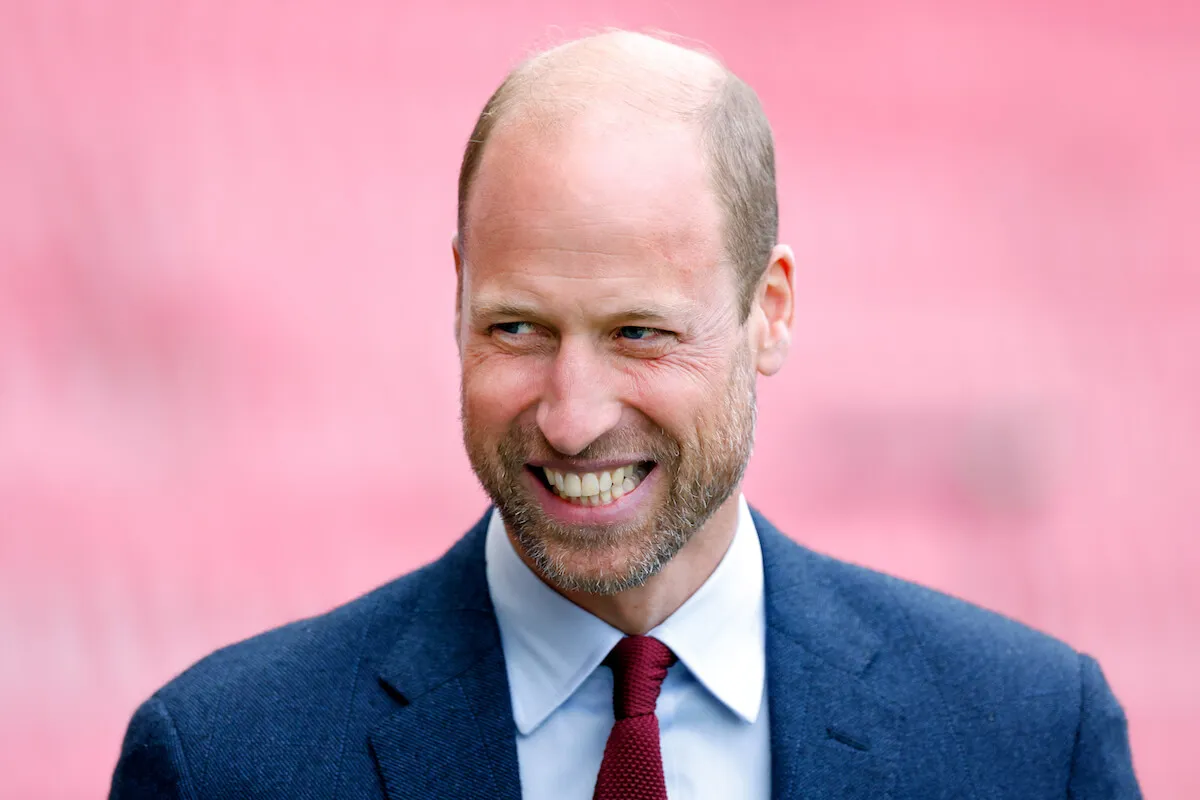 Prince William, who shared what he's looking forward to over Christmas, smiles and looks on wearing a suit and tie.