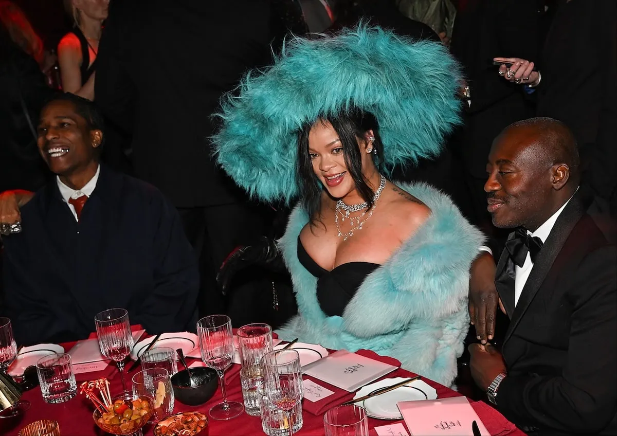 Wearing a fluffy blue dress and hat, Rihanna sits between A$AP Rocky and British fashion editor Edward Enninful