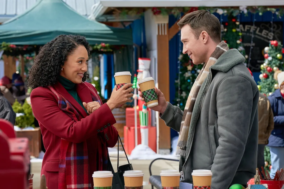 Tamera Mowry-Housley and Carlo Marks toasting with coffee cups in the Hallmark movie 'Scouting for Christmas'