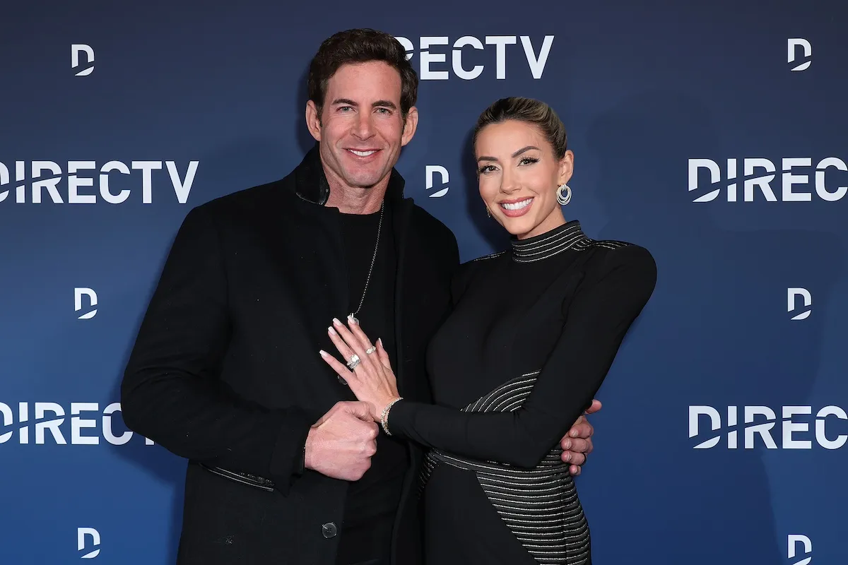 Tarek El Moussa and Heather Rae El Moussa pose for a photo in front of a DirecTV backdrop