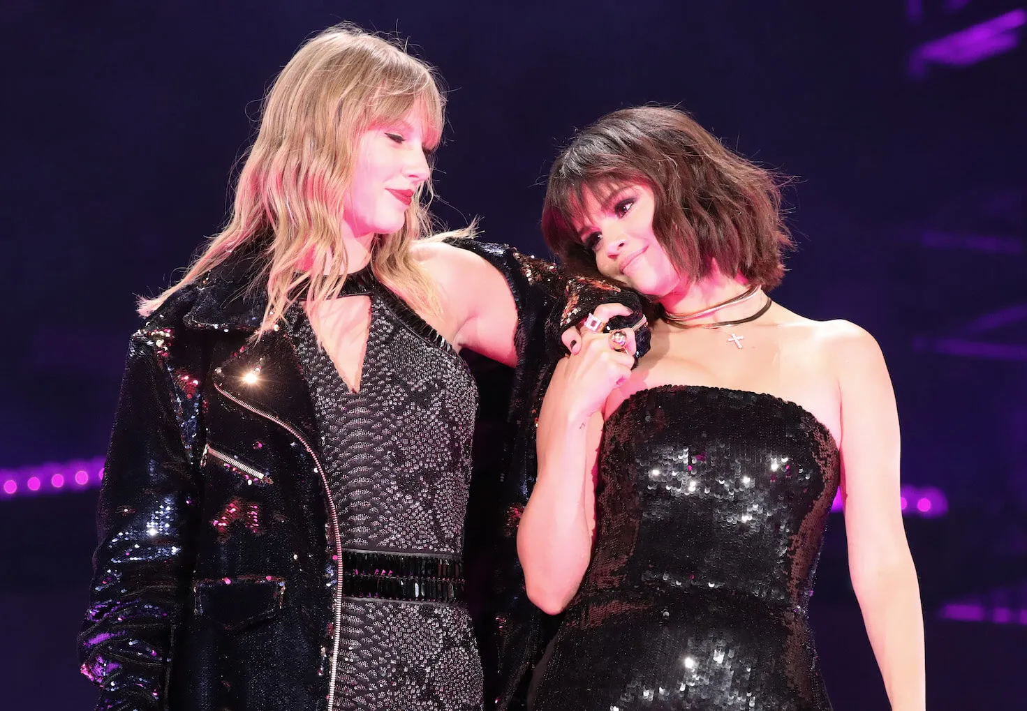 Selena Gomez leaning on Taylor Swift's shoulder as Swift looks down at her during the 'Reputation' tour in 2018