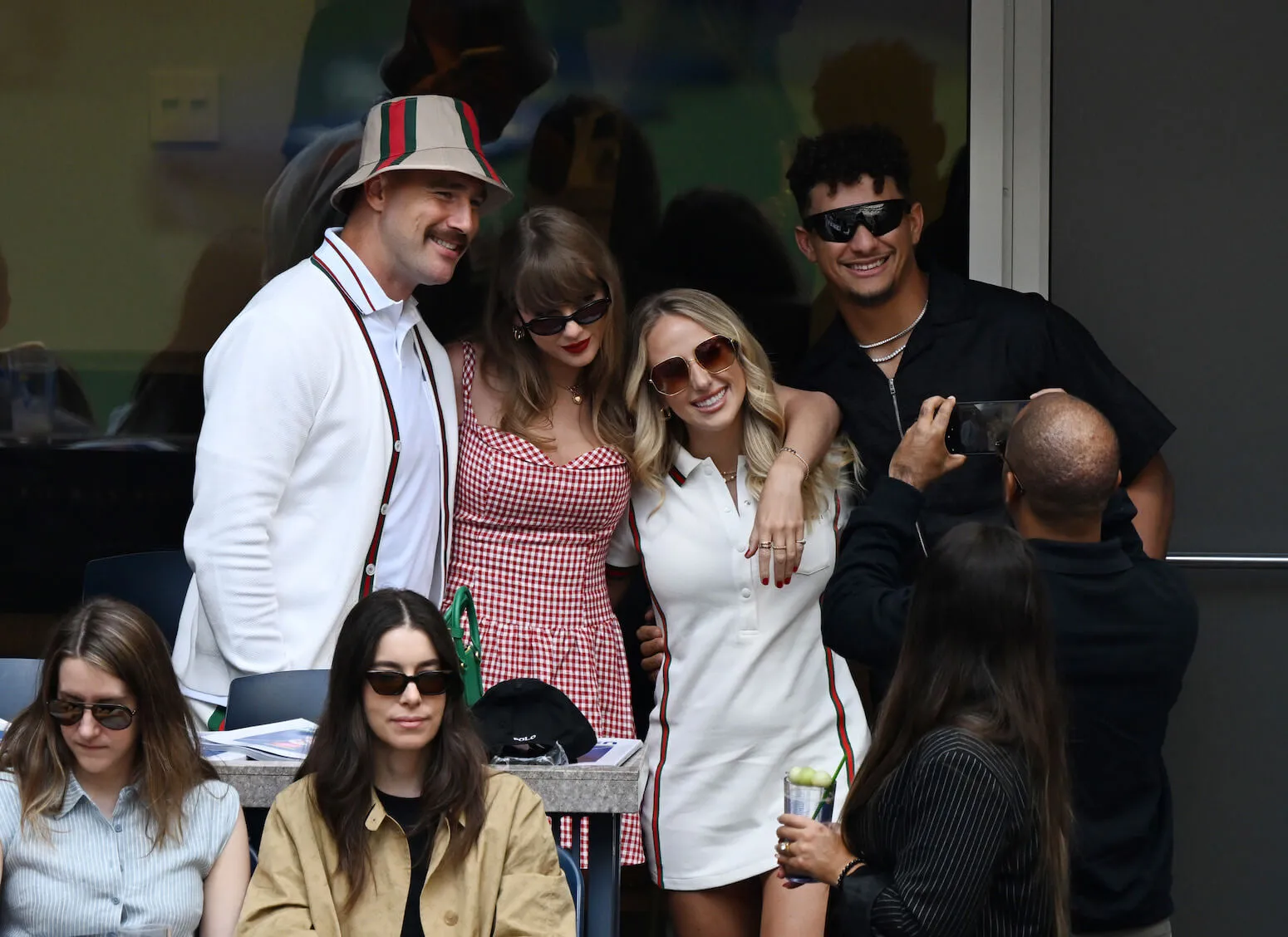 Travis Kelce, Taylor Swift, Brittany Mahomes, and Patrick Mahomes posing for a photographer with their arms around each other at the 2024 US Open