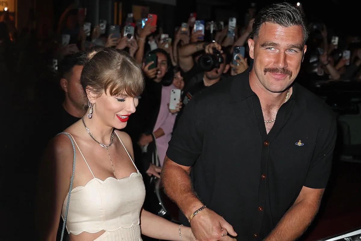 Taylor Swift and Travis Kelce hold hands as they walk through a crowd in New York City in September 2024