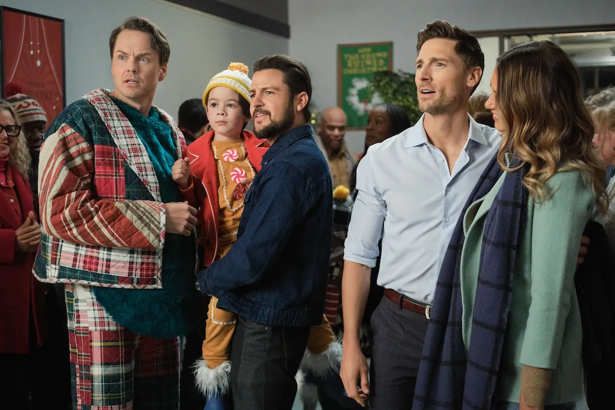 Three men looking at something, with the second from the left holding a toddler on his hip in the Hallmark movie 'Three Wiser Men and a Boy'