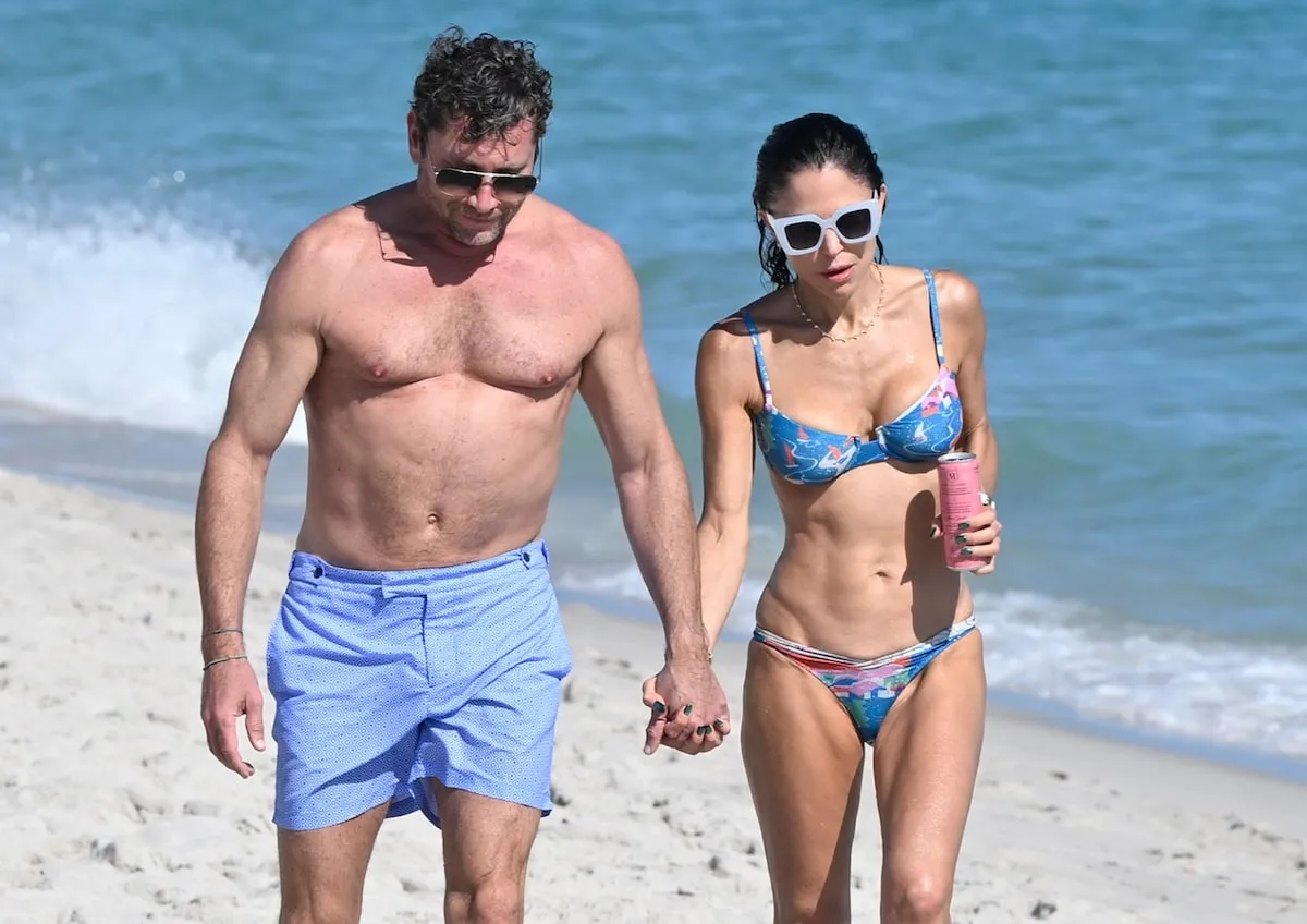 Wearing a blue floral bikini, Bethanny Frankel walks on a Miami beach with her boyfriend, Tom Villante