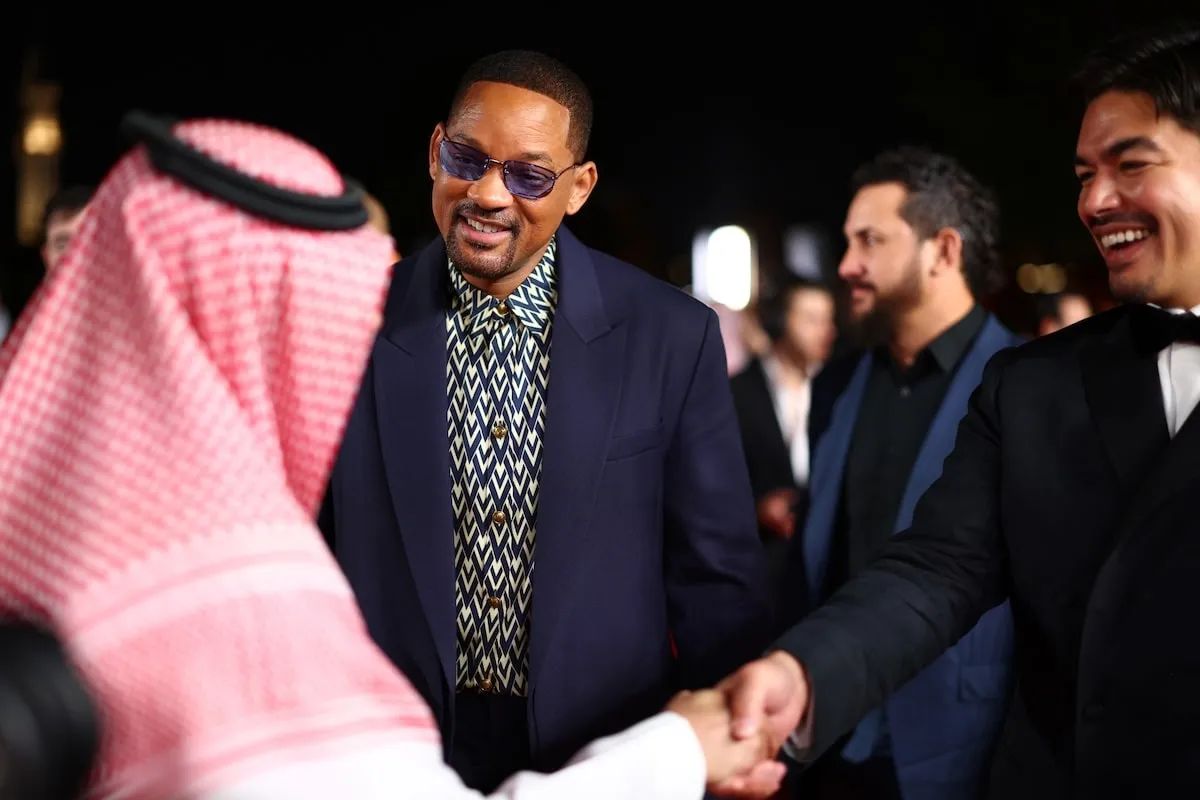 Wearing a navy suit, Will Smith greets a supporter at the Opening Ceremony at the Red Sea International Film Festival 2024