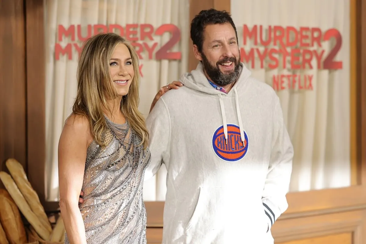 Jennifer Aniston and Adam Sandler posing in a dress and hoodie respectively for 'Murder Mystery 2'.