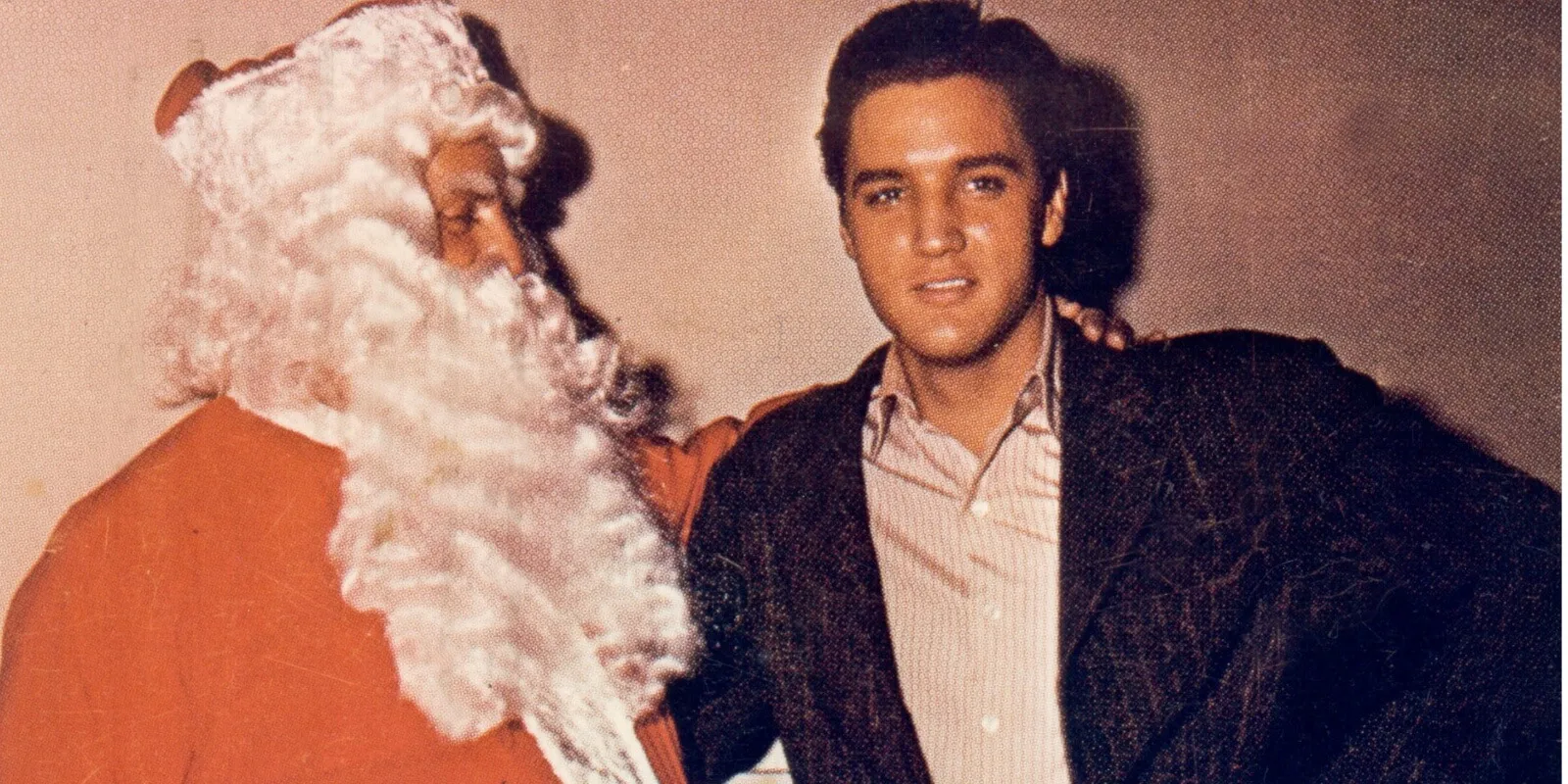 Elvis Presley poses with Colonel Tom Parker (dressed as Santa Claus)in this Christmas card circa 1965.