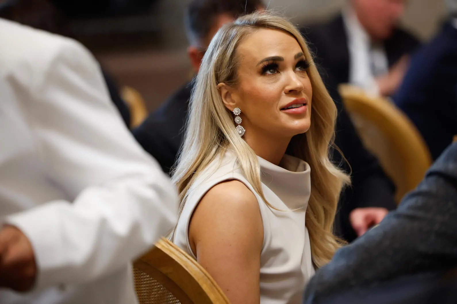 Carrie Underwood sitting and looking up at the 2nd inauguration of Donald Trump. She's wearing a sleeveless dress.