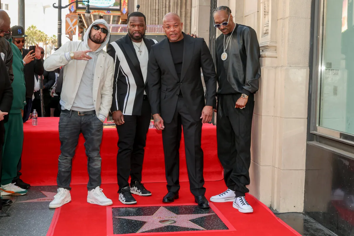 Eminem, 50 Cent, Dr. Dre, and Snoop Dogg stand together above a Hollywood Walk of Fame star.