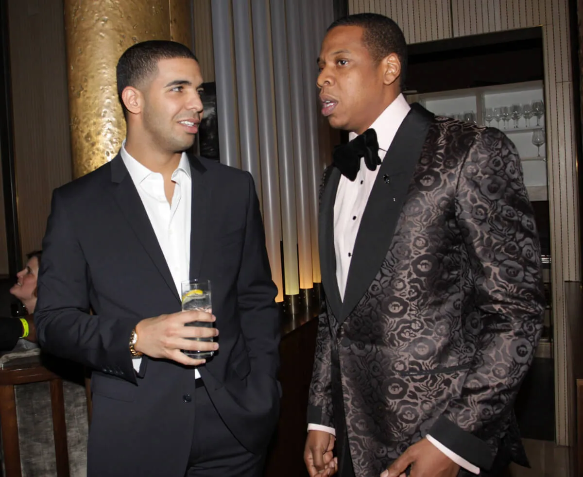 Drake wears a suit and stands with Jay-Z, who wears a tuxedo.