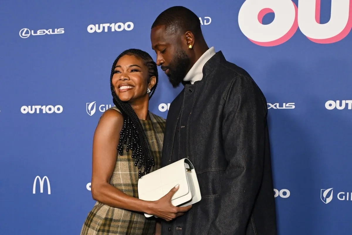 Gabrielle Union smiles on the red carpet as Dwyane Wade admires her