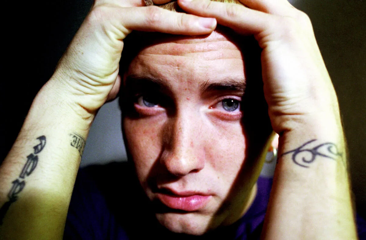 A close up picture of Eminem with his hands on his head.