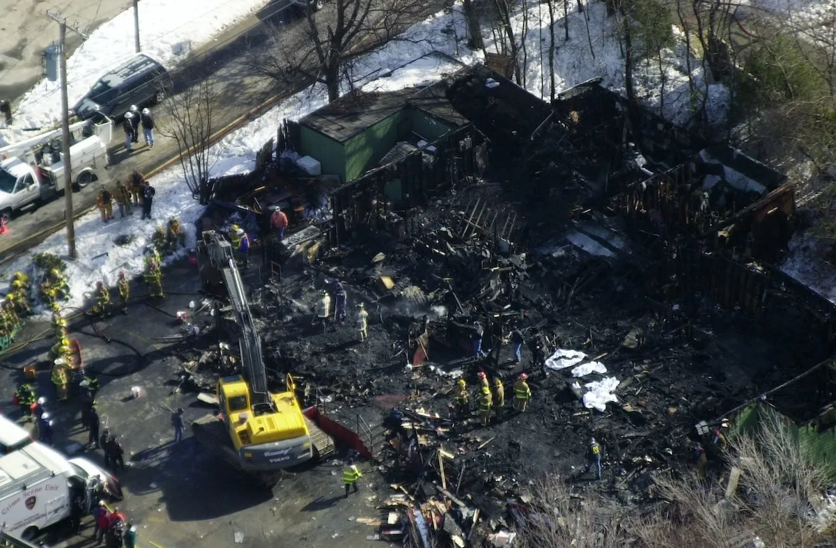 Rescue workers, firefighters, and police officers pull bodies from the burned-out remains of The Station