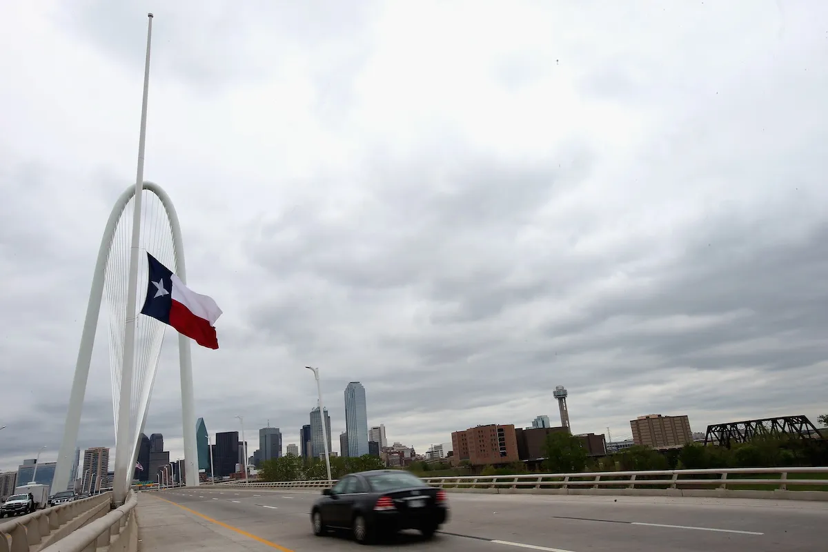 Texas state flag at half-mast next to a highway