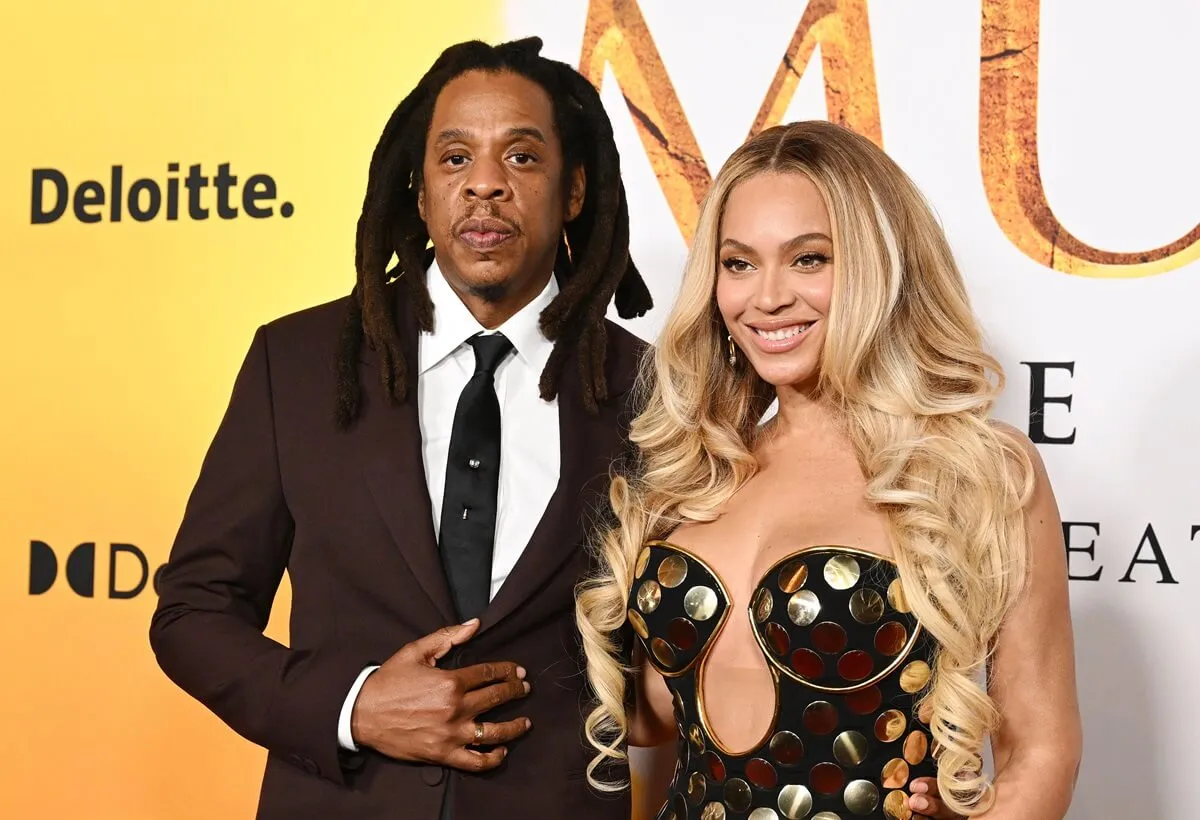 Beyoncé in a dress posing next to Jay-Z in a brown suit at the premiere of 'Mufasa'.