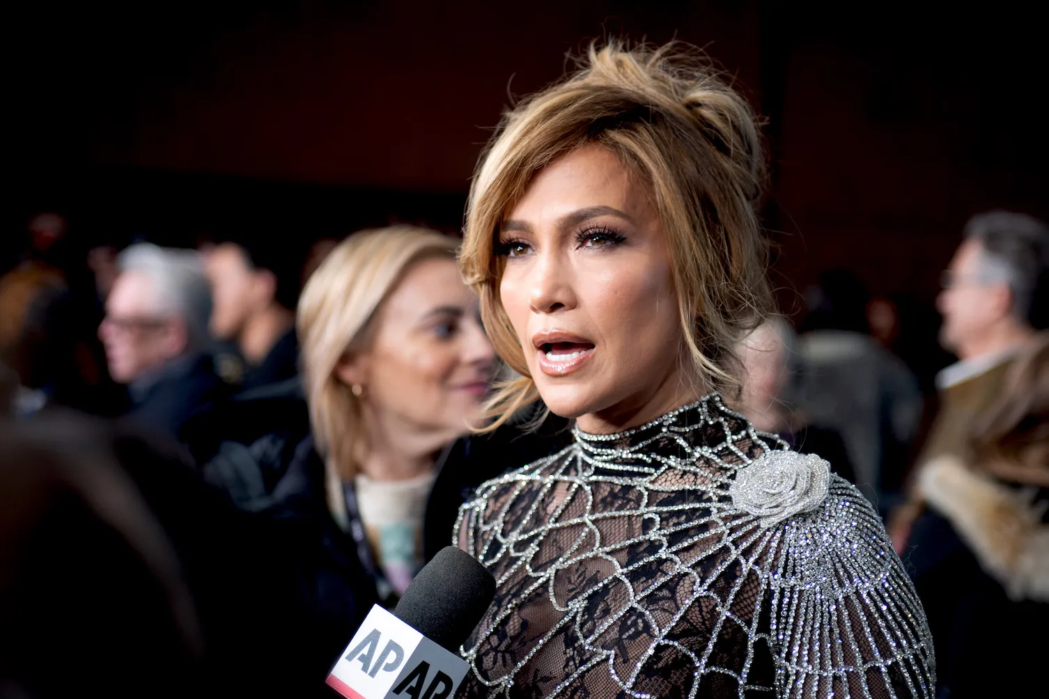 Jennifer Lopez in a spider web dress for 'Kiss of the Spider Woman' speaking into a microphone