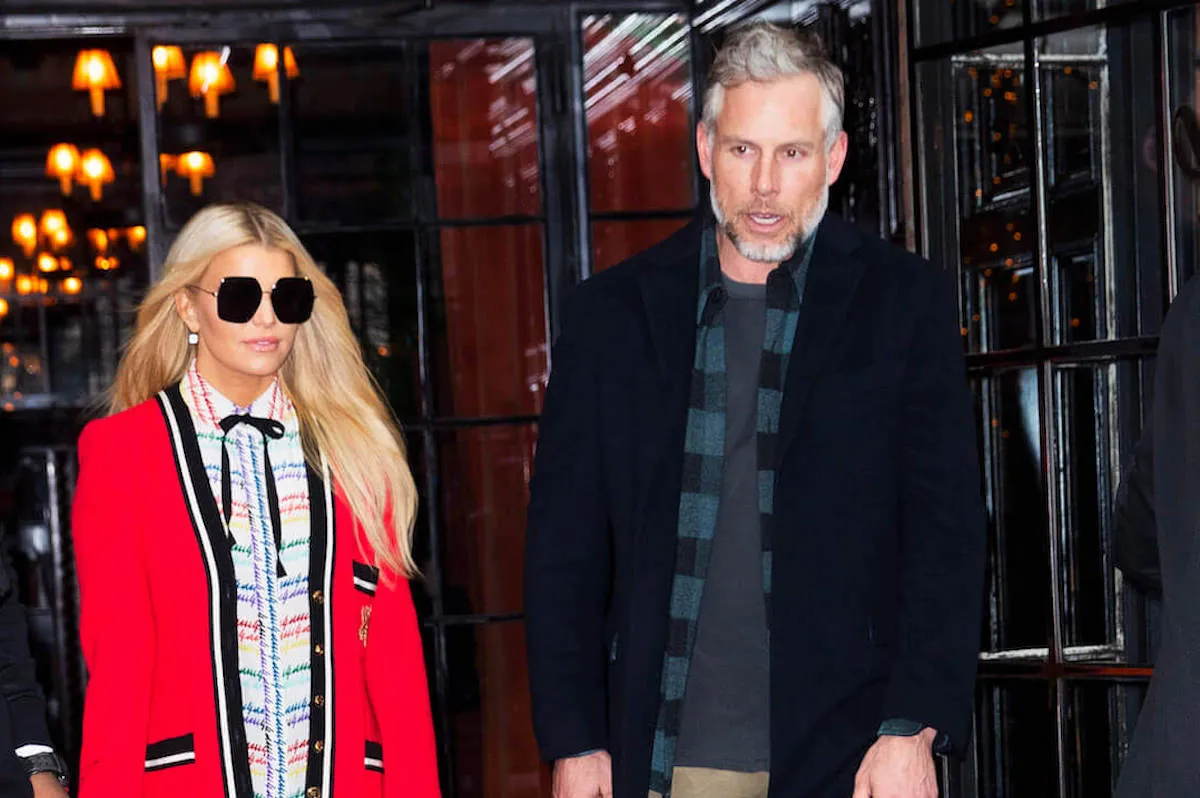 Jessica Simpson in a red coat over a colorful blouse standing next to Eric Johnson in New York City