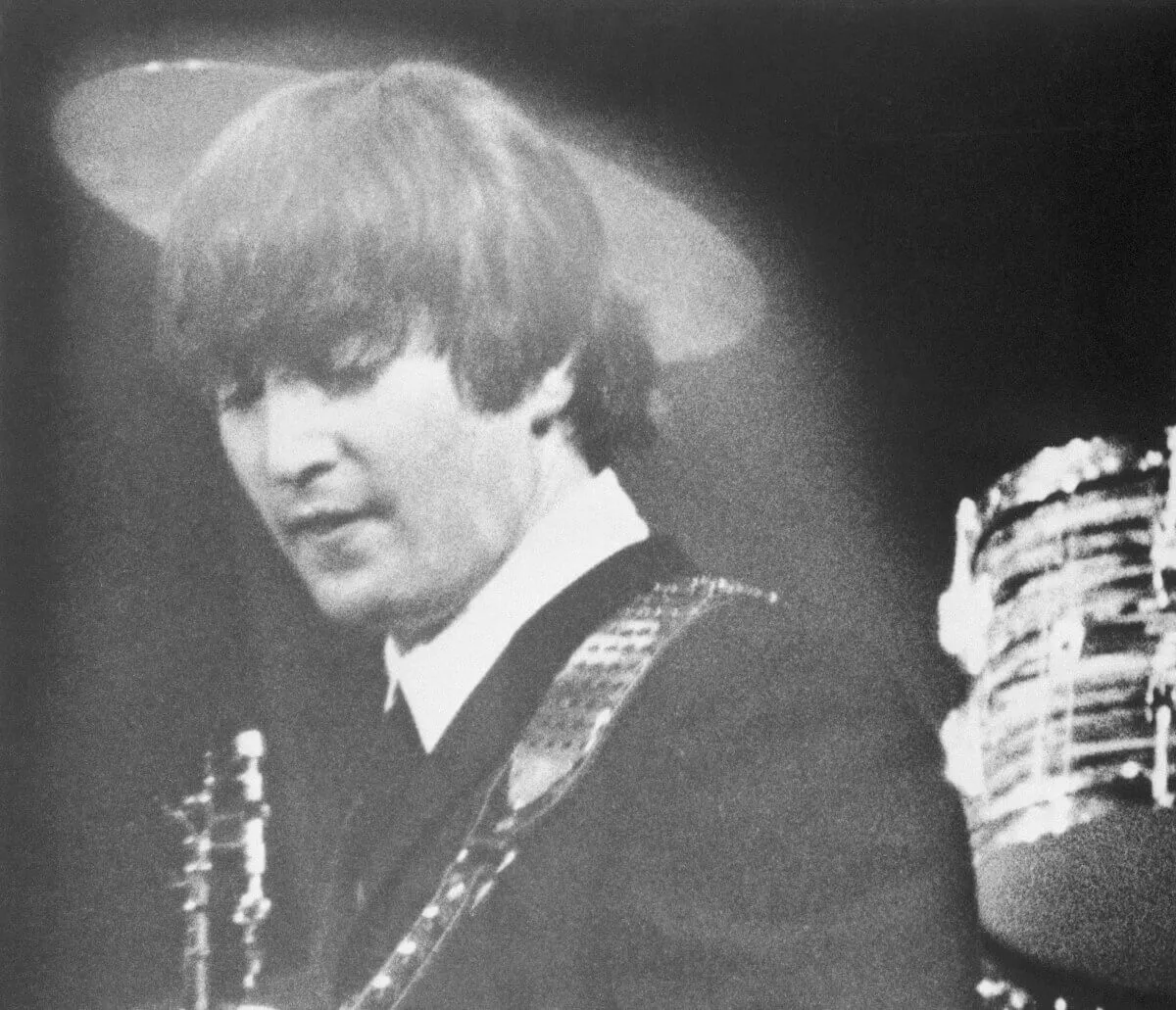 A black and white picture of John Lennon playing guitar.