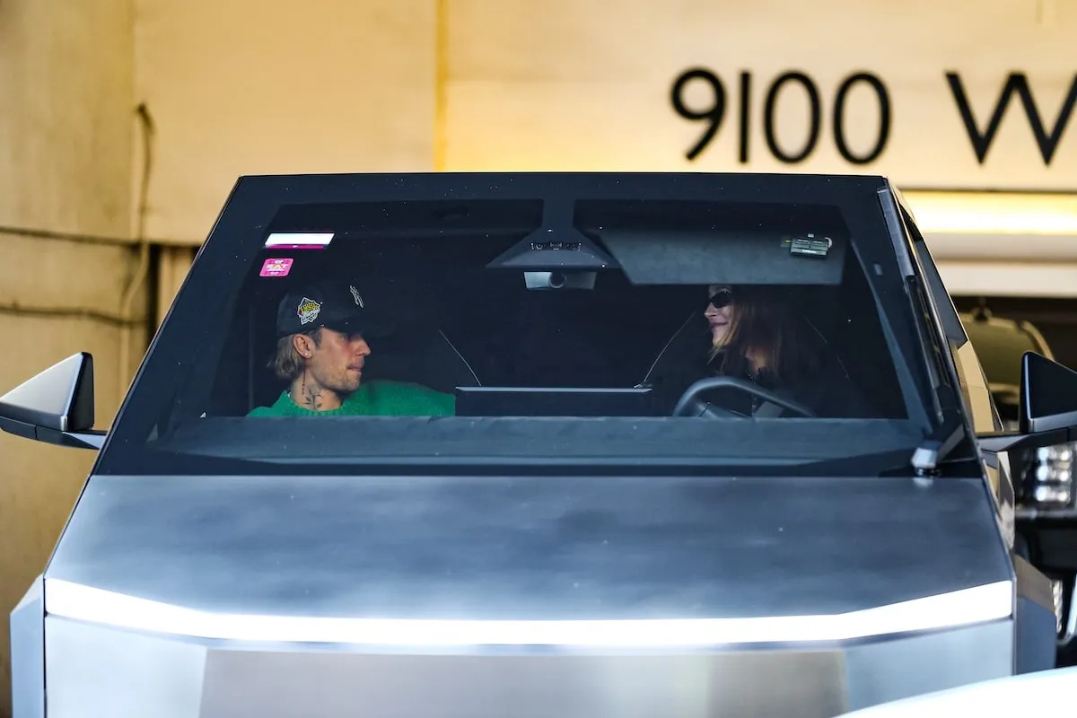 Smiling at each other, Justin Bieber and Hailey Bieber exit a parking garage in their Tesla Cybertruck