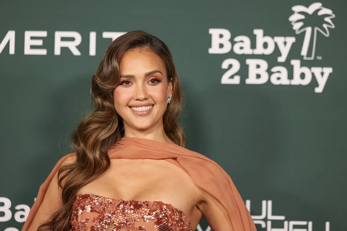 Jessica Alba posing in an orange dress at the 2024 Baby2Baby Gala.