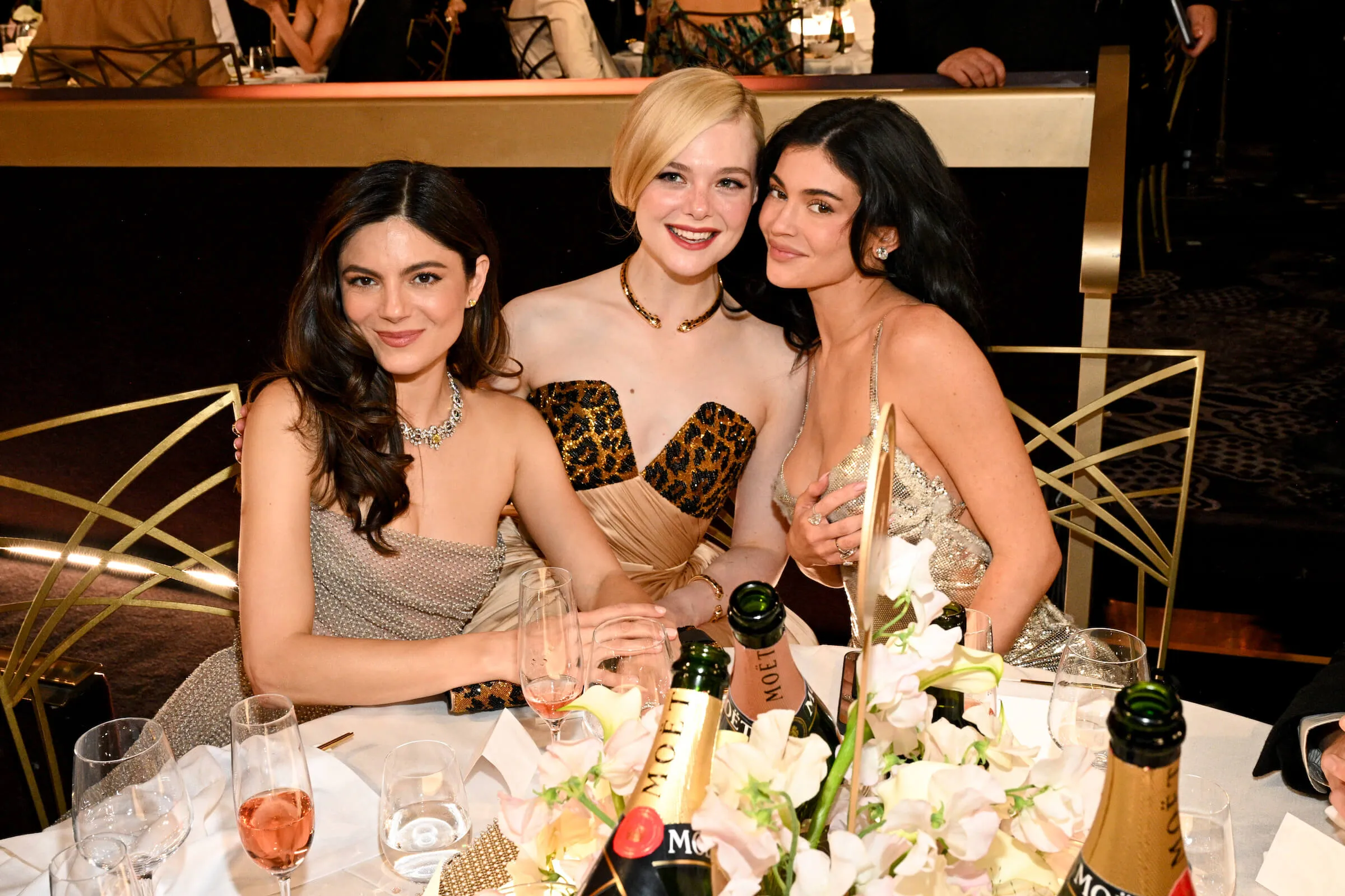 Monica Barbaro, Elle Fanning, and Kylie Jenner sitting next to each other and posing at the 82nd Annual Golden Globes