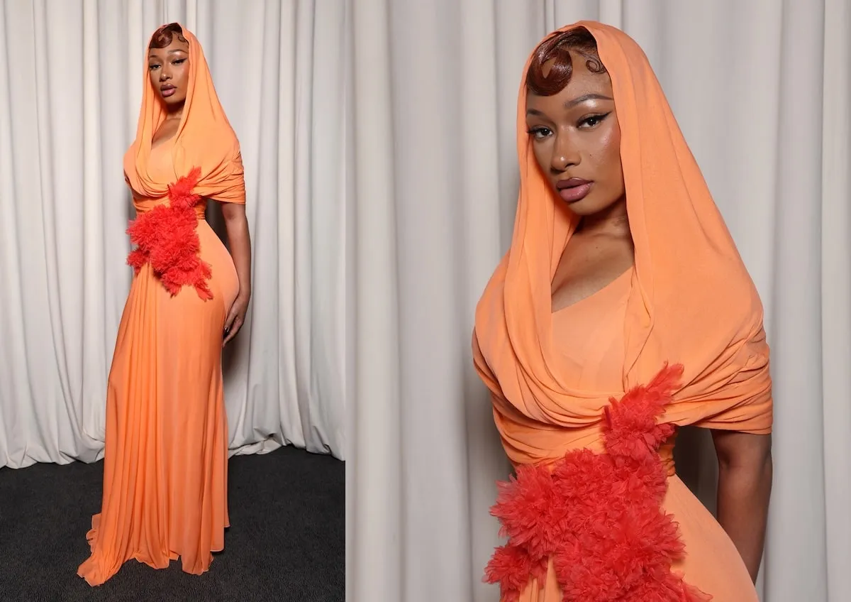 Wearing an orange gown, Megan Thee Stallion smiles for cameras at the Giambattista Valli Haute Couture Spring-Summer 2025 show