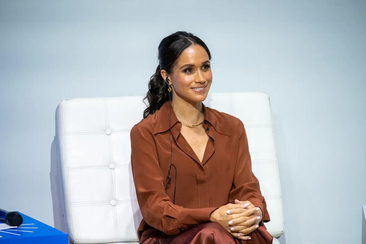 Wearing a Cartier Juste Un Clou Necklace, Meghan Markle smiles on stage at a 2024 summit