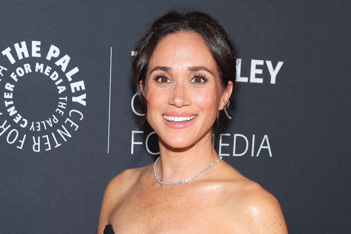 Meghan Markle, who will 'fine' if her Netflix show, 'With Love, Meghan,' fails, according to a commentator, smiles posing on the red carpet.