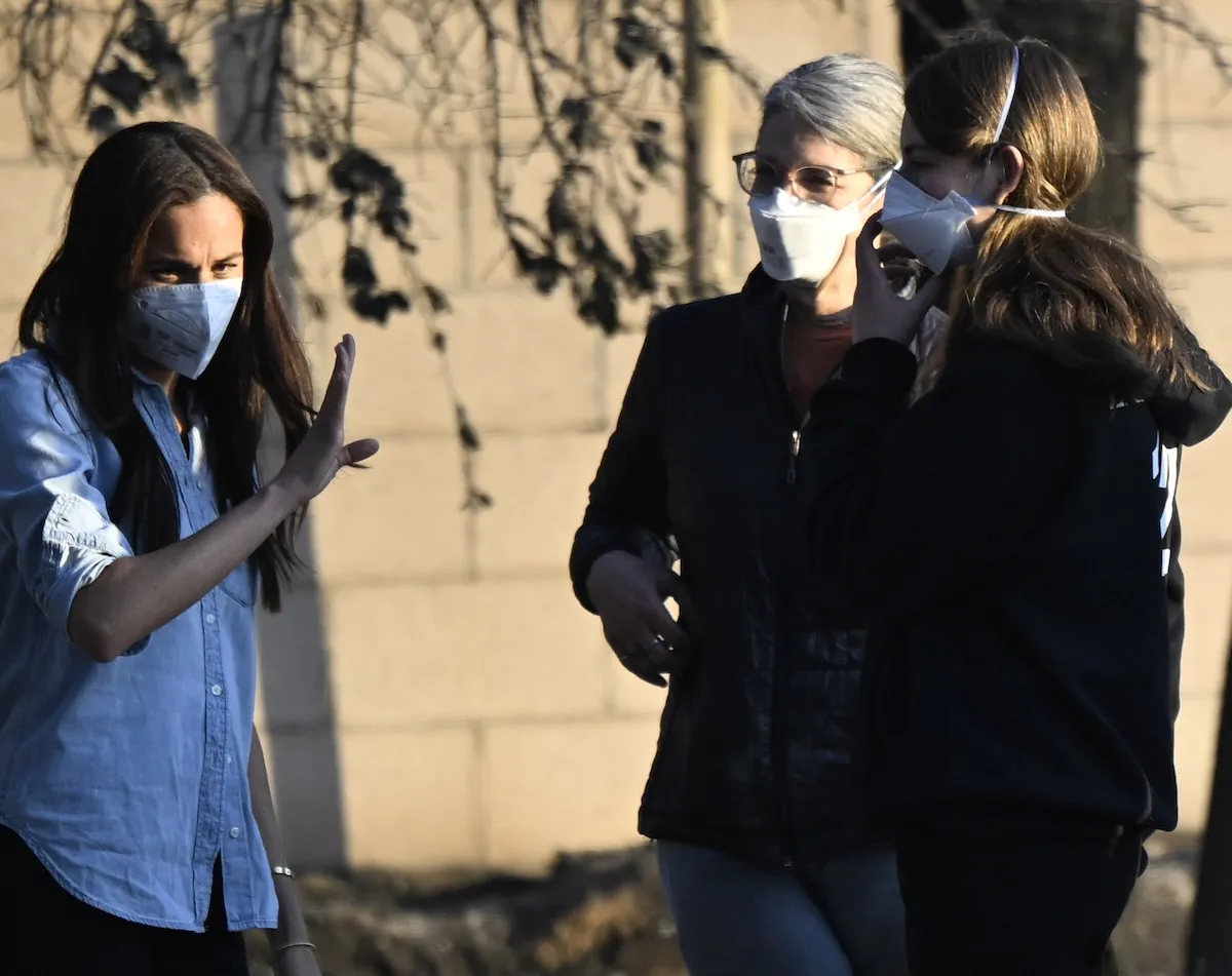 Meghan Markle, wearing a mask, speaks with two other women near a home in Altadena, Calif. that was destroyed in a fire